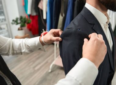 Cropped photo of tailor adjusting length of sleeve on client using pins